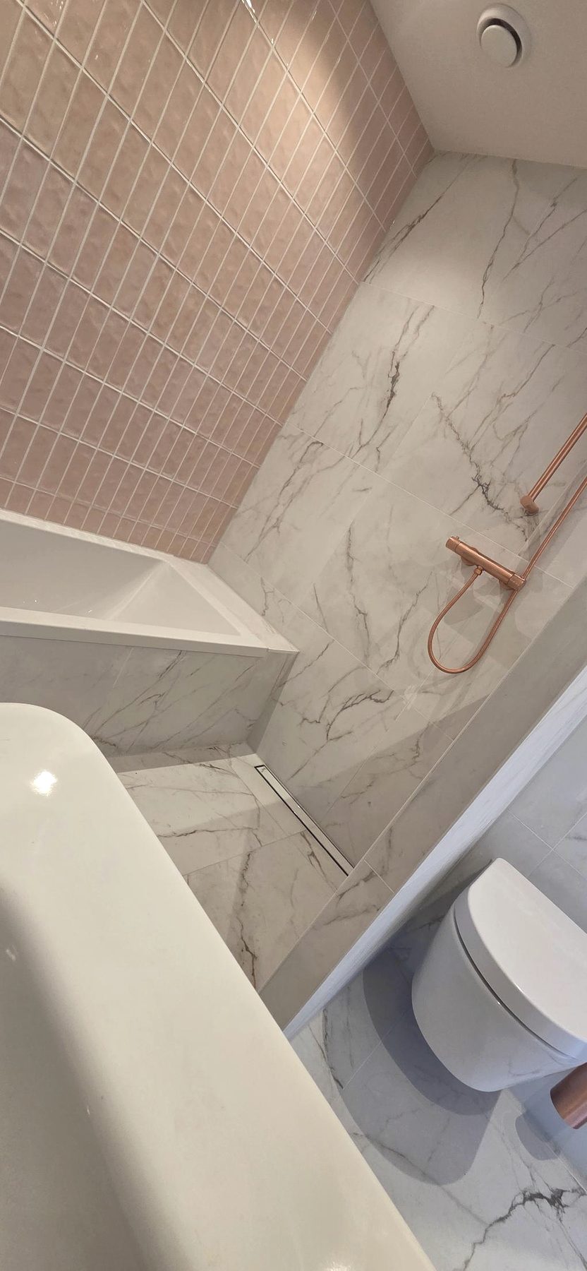 Geplaatste badkamer met bad, marmer en koperen douche