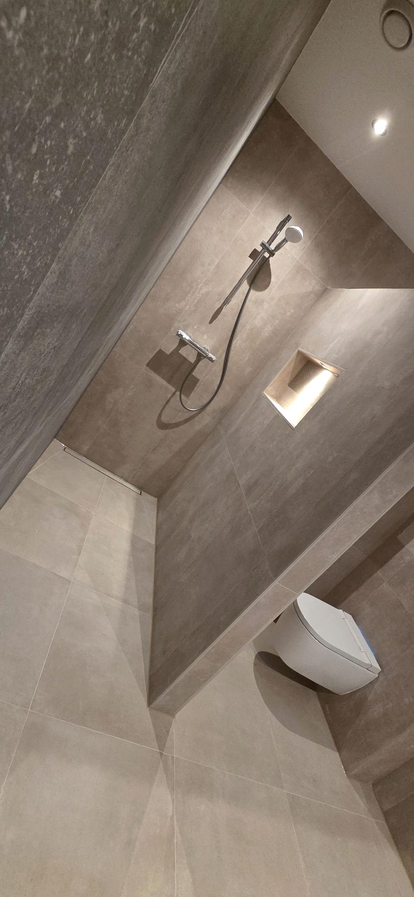 Geplaatste douche in warme tegels met verlichte nis