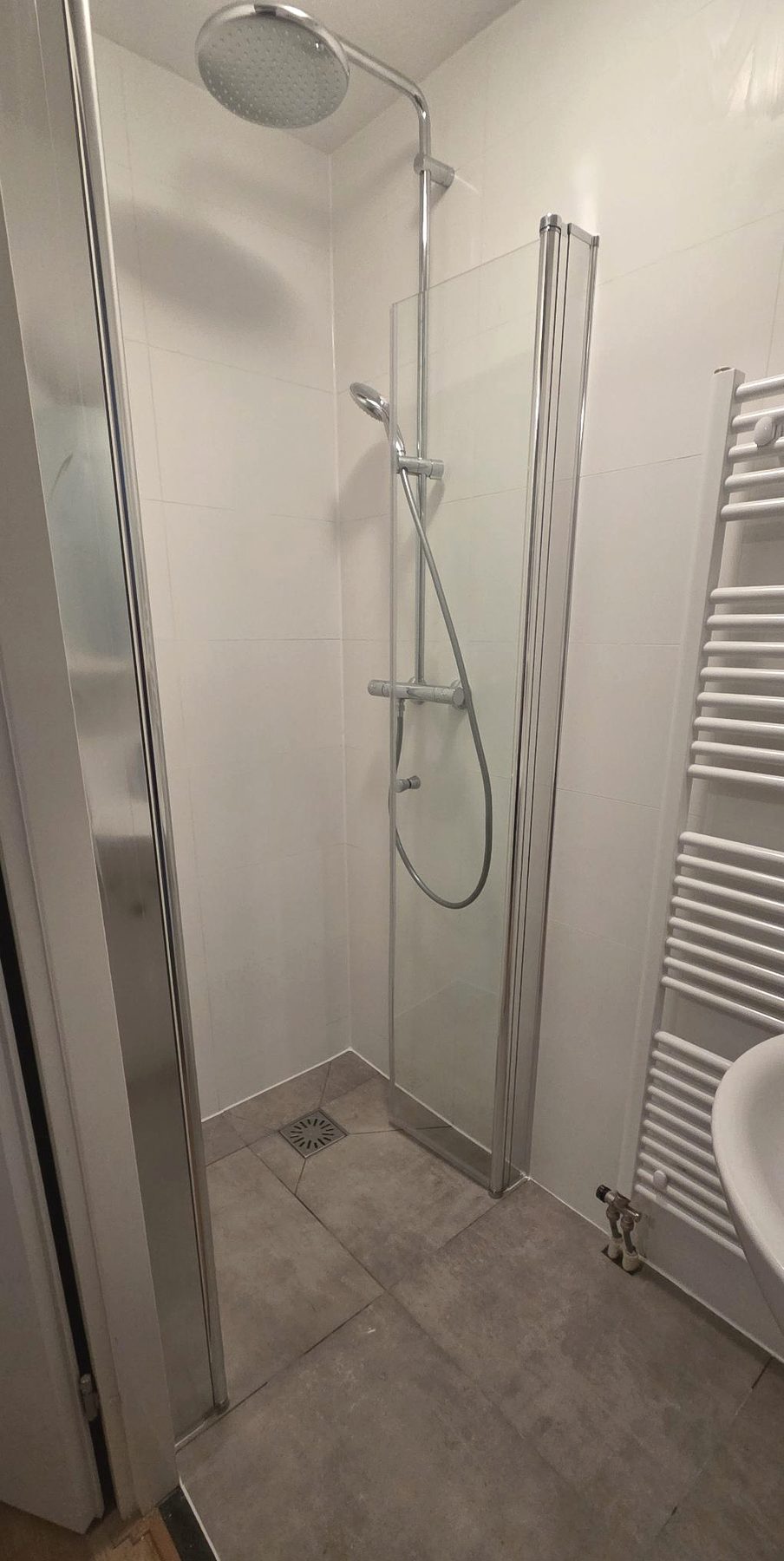 Geplaatste witte douche met chromen set en glazen wand