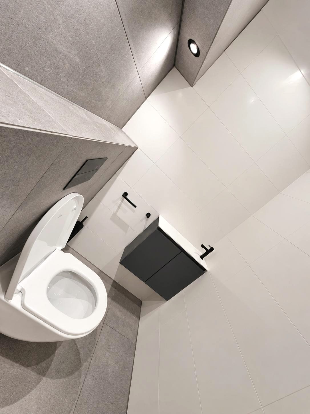 Geplaatst toilet met grijs en wit tegelwerk en een zwart fonteinmeubel
